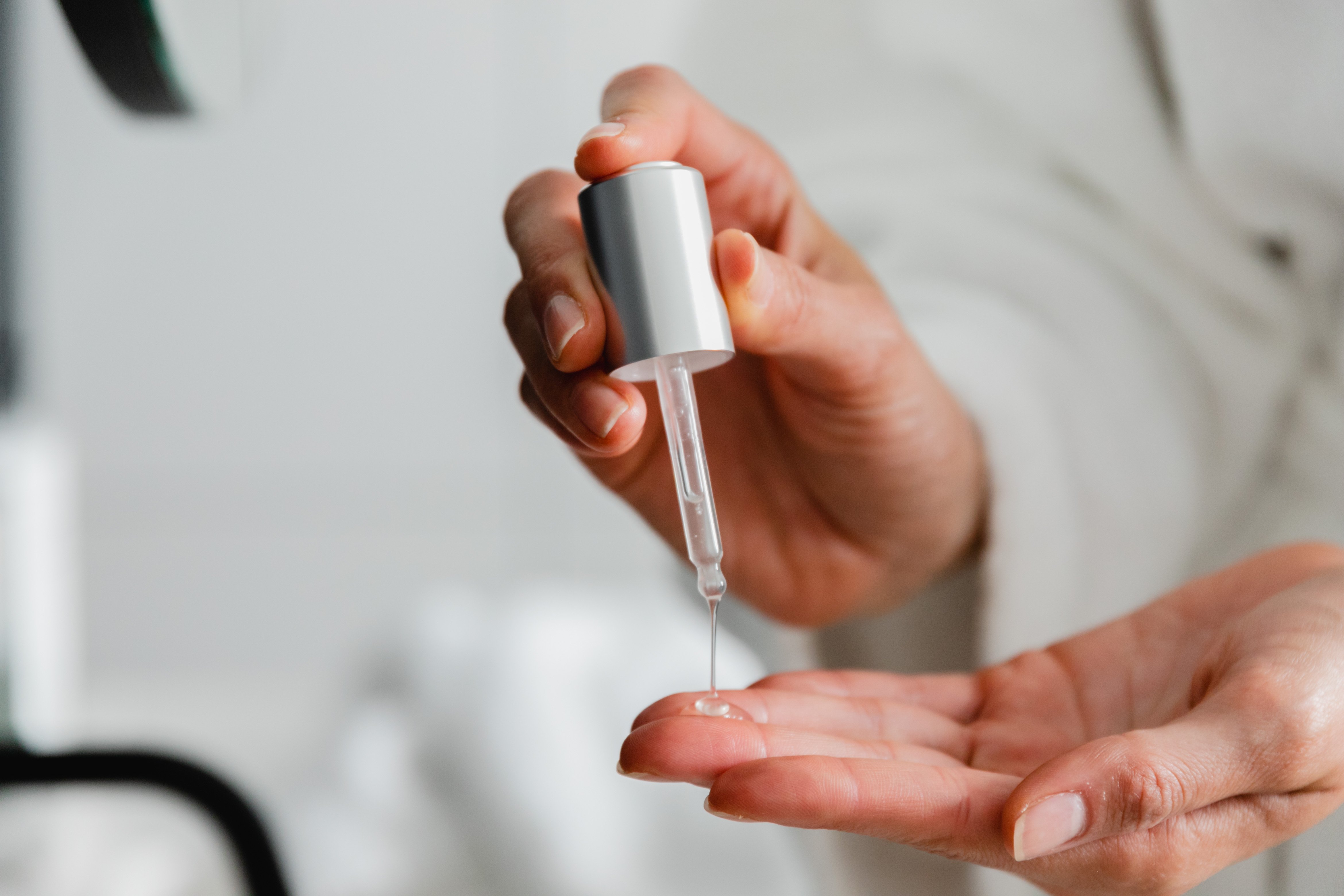 Hyaluronic Acid serum dripping from bottle