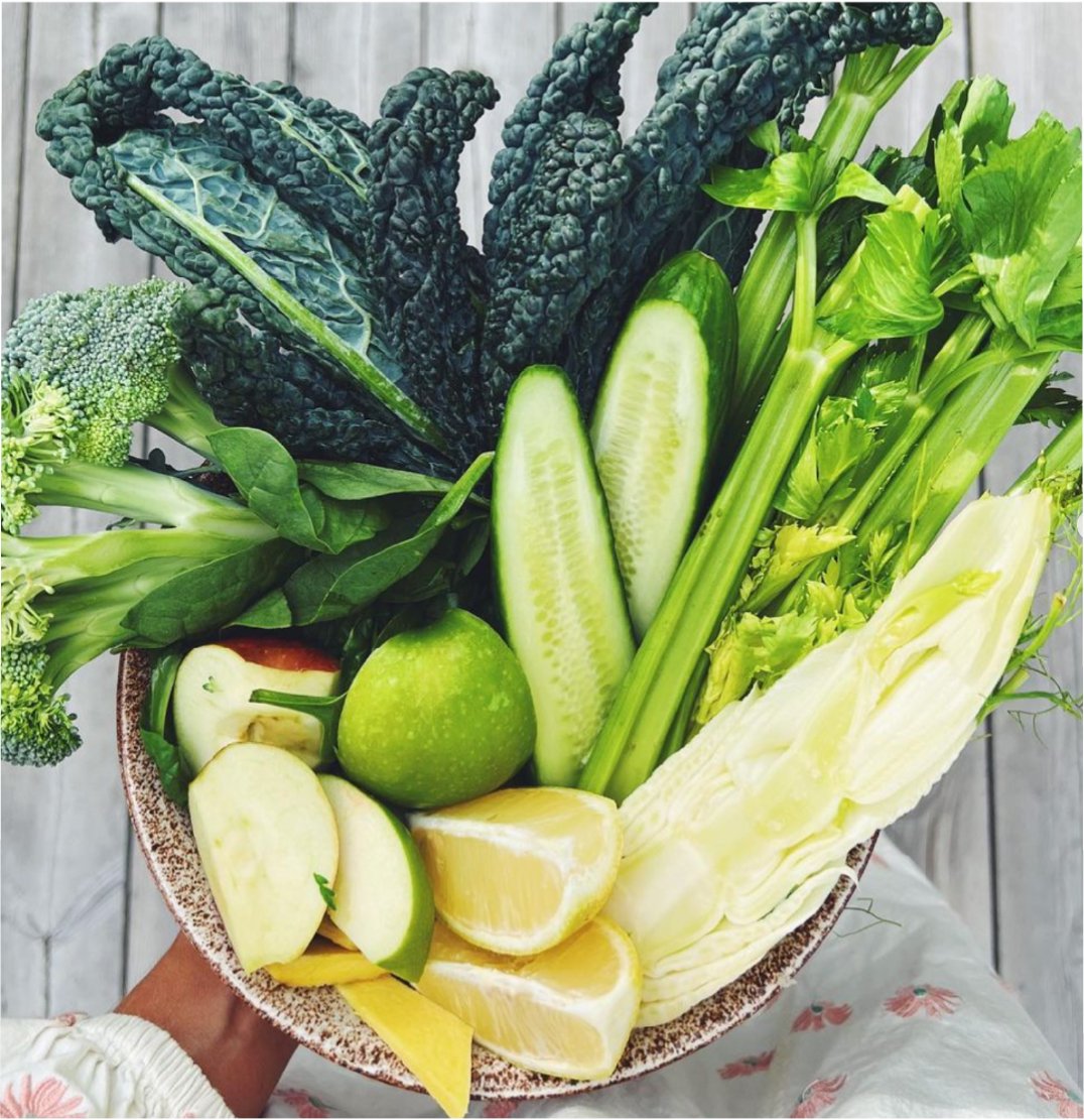 Person holding a beautiful bow of fresh produce kale cucumbers fennel celery and more