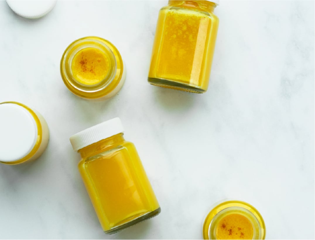 5 small jars of immune builder shot on a marble surface.