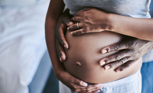 A pregnant woman and her partner holding her pregnant tummy.