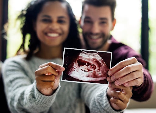 Parents-to-be hold up a scan of their unborn child.