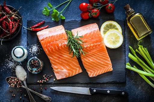 Wild salmon fillets with salt pepper, seasoning, lemon and tomatoes. Salmon is one of the best foods to eat during pregnancy.