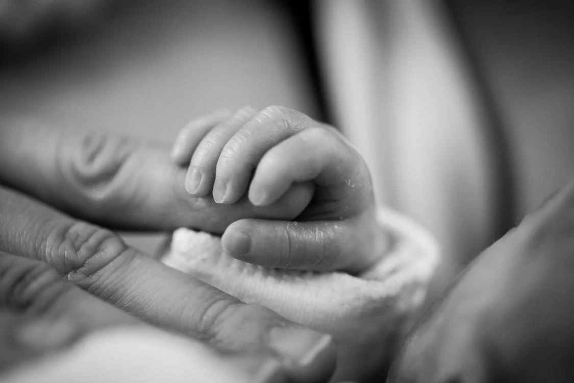 Close-up of baby holding parents’ finger 