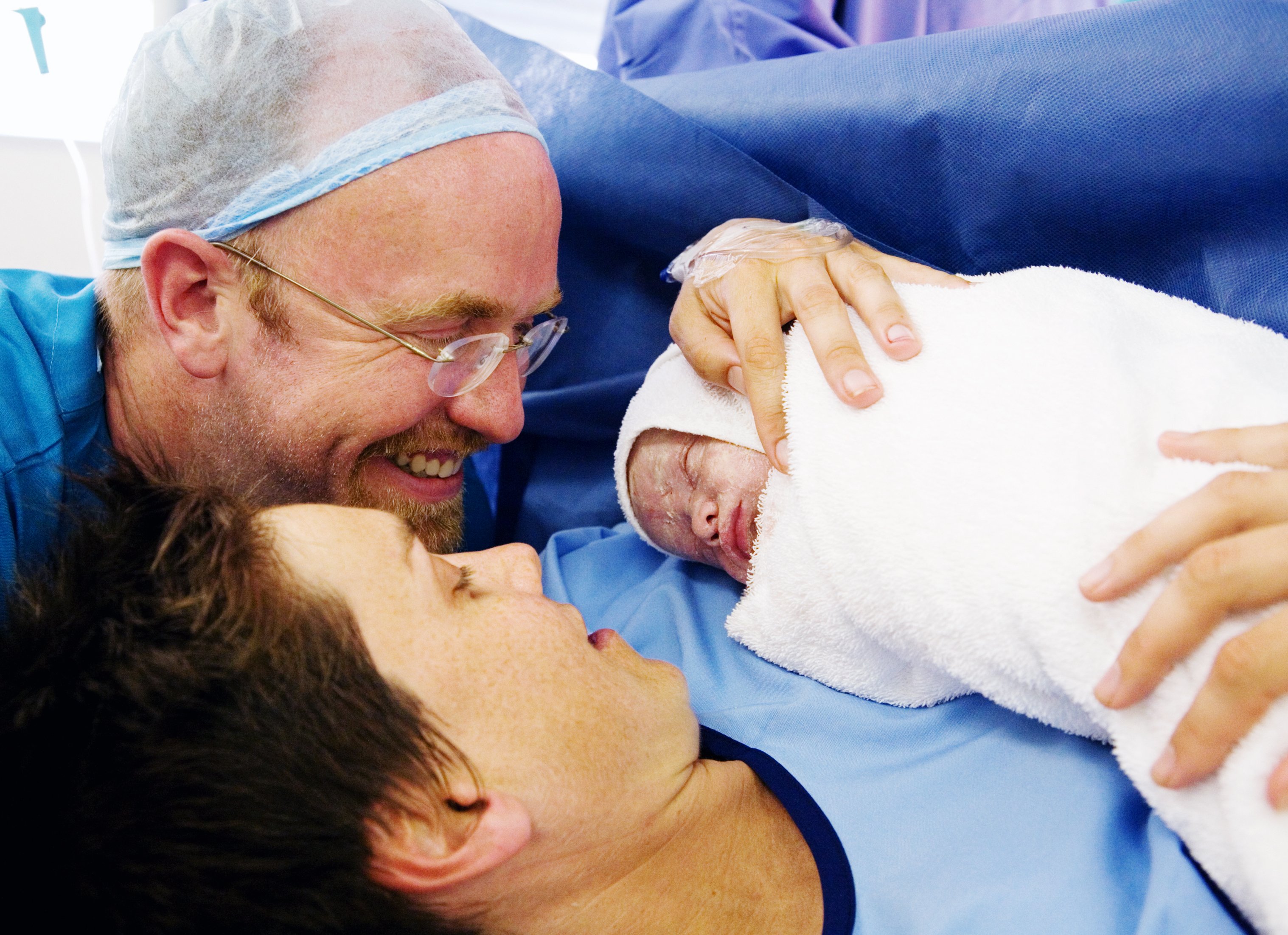 father and mother holding their newborn baby