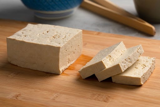 Tofu sliced on a chopping board. Tofu is a good food to include in a pregnancy diet.