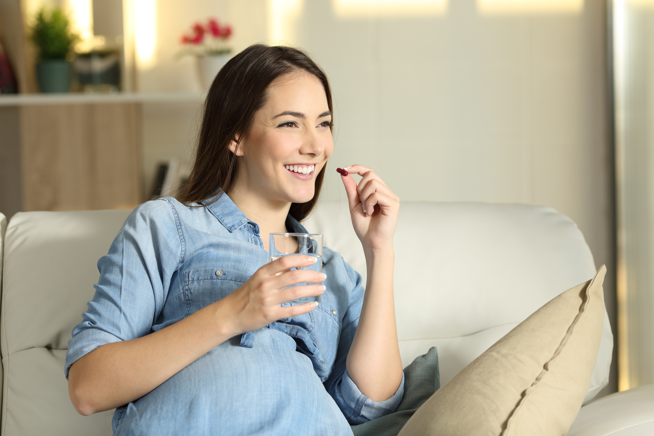 Happy pregnant woman takes an iron supplement at home