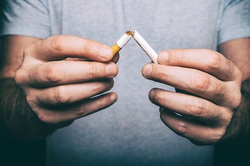 A man breaking a cigarette in two. Stopping smoking is a good way to increase sperm count.