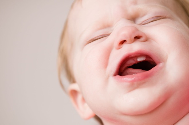 A teething baby crying from baby teething pain.