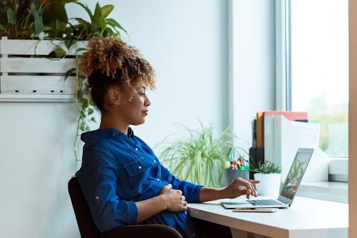 A pregnant woman is researching when to book antenatal classes on her laptop.