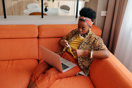 woman holding a thermometer while sitting on a sofa