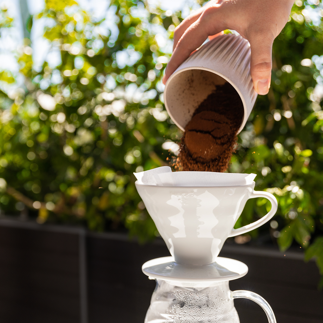 putting ground coffee into a pour over