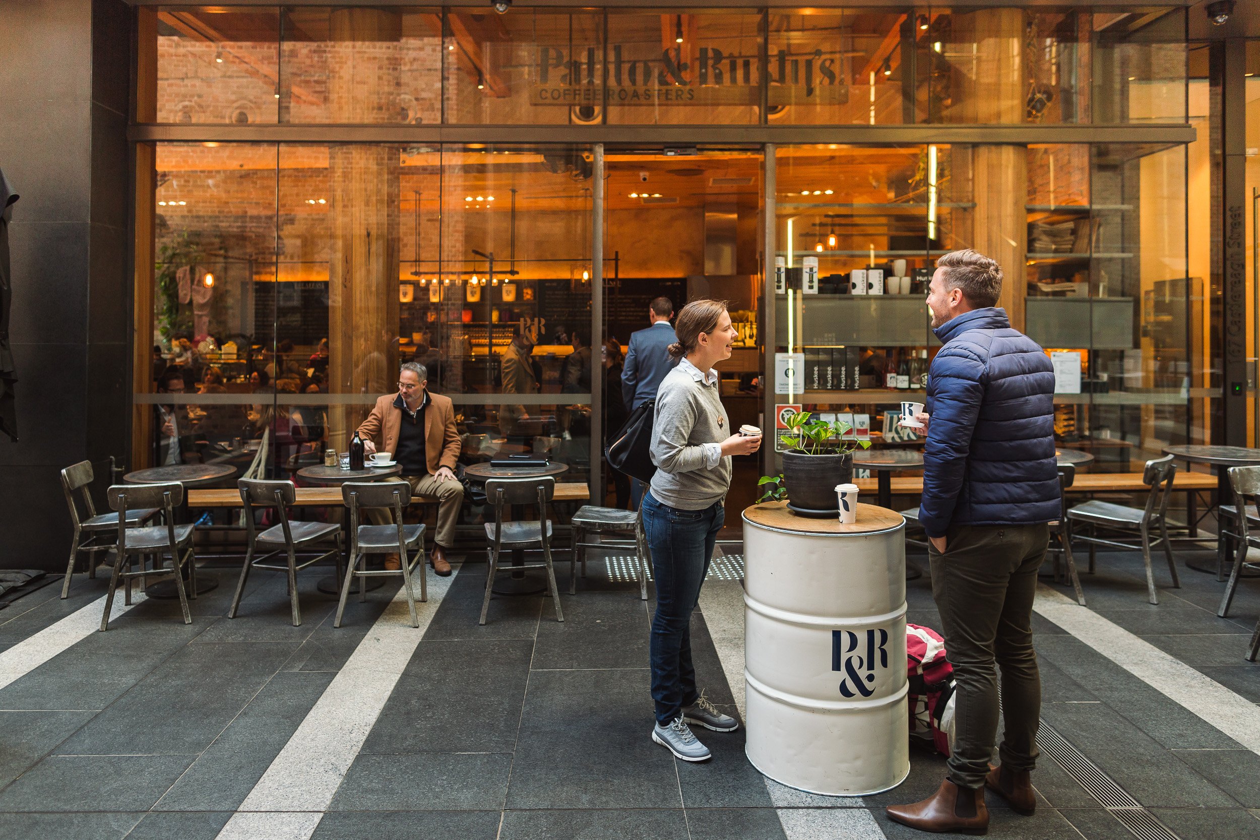 Two people standing outside a cafe with a coffee in their hand