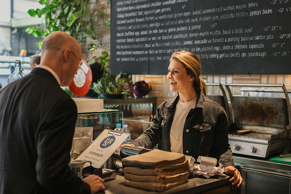 Cafe staff handling a customer ordering coffee 