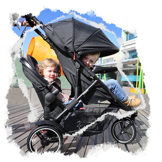 two toddlers being pushed along boardwalk in their inline double pram - philandteds dot with double kit inline pram