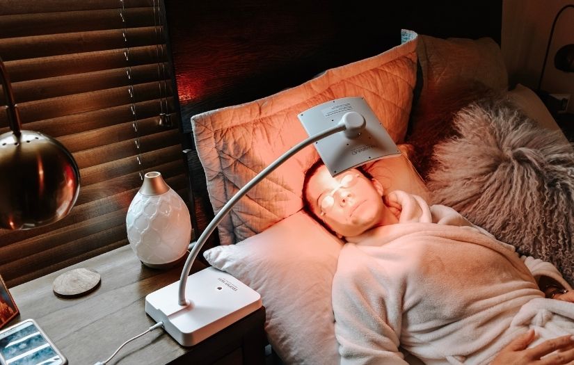 woman using red light therapy on bed