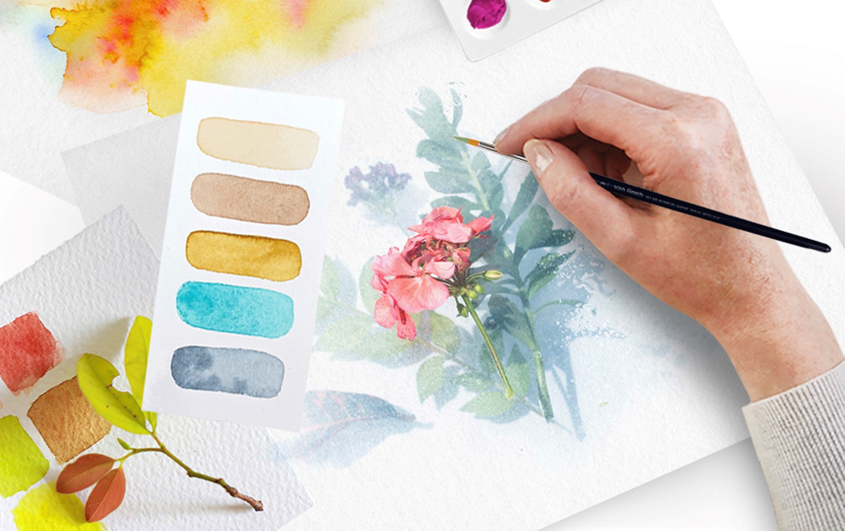 Artiste peignant une fleur à l'aquarelle sur le papier d'art qu'elle a choisi, entourée d'échantillons de couleurs et d'autres échantillons de papier.