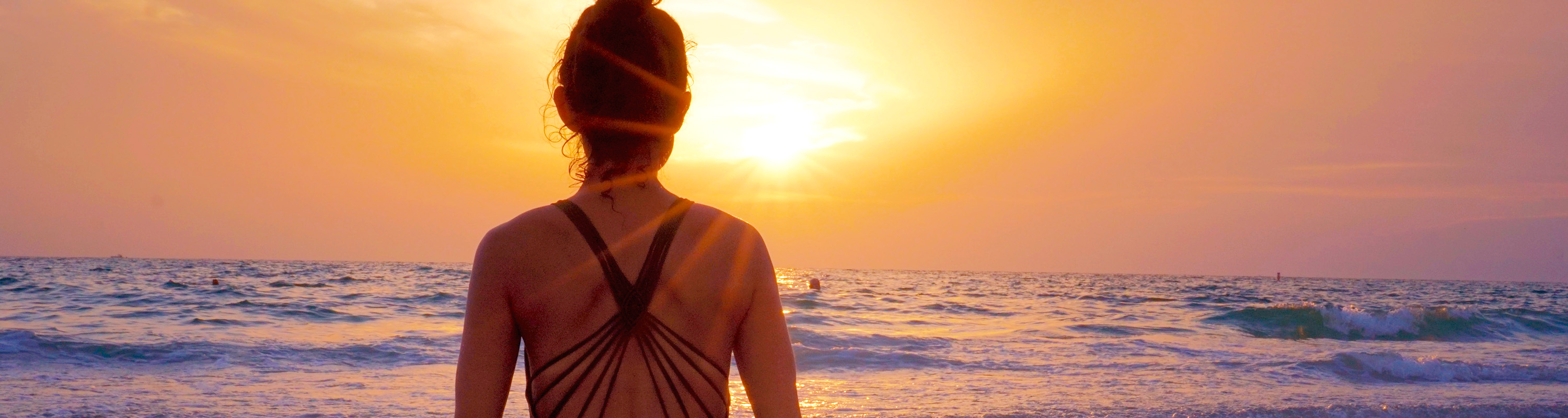 Female facing the ocean and sunset on Spring Break.