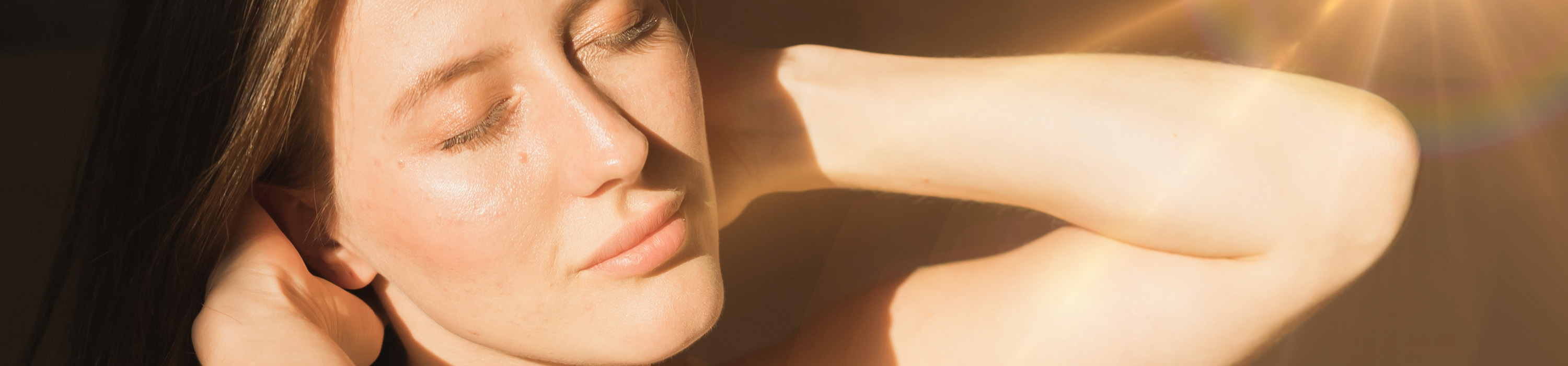 Female with eyes closed basking in the sunlight with a healthy glow from glowoasis vegan probiotic skincare.