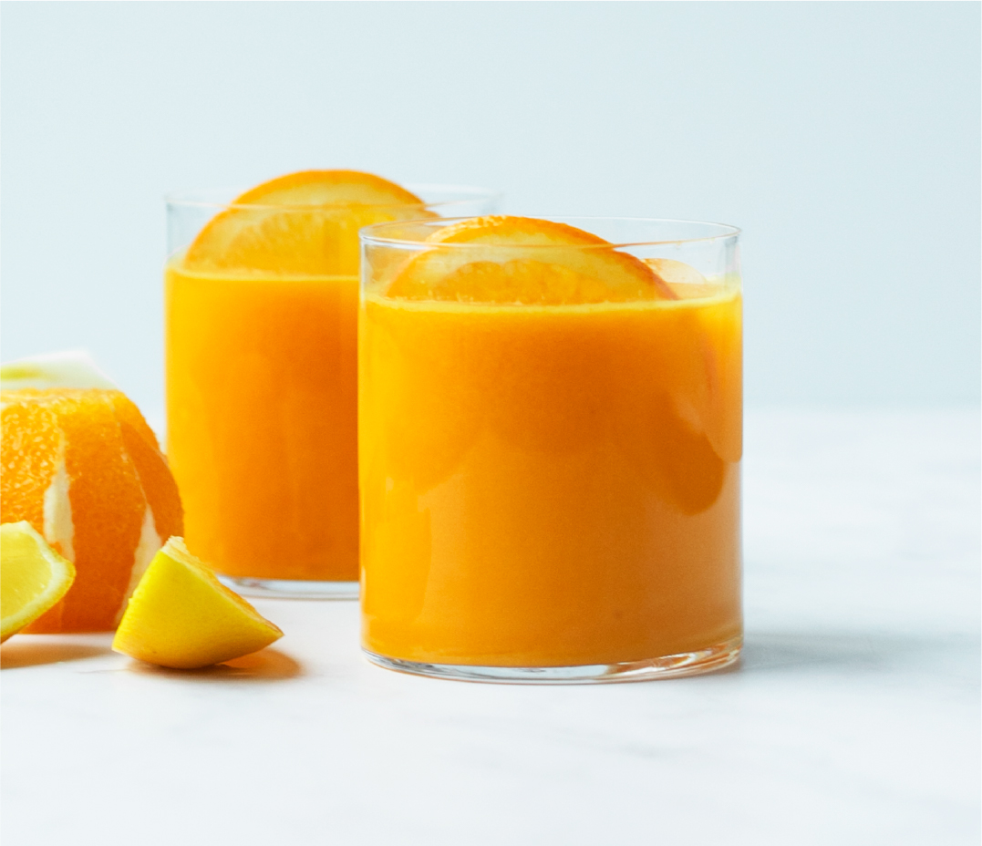 two glasses of orange juice each garnished with a slice of orange