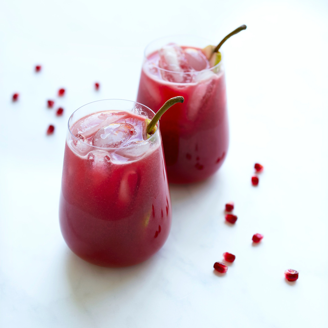 2 glasses of red crimson pear juice on ice with straws
