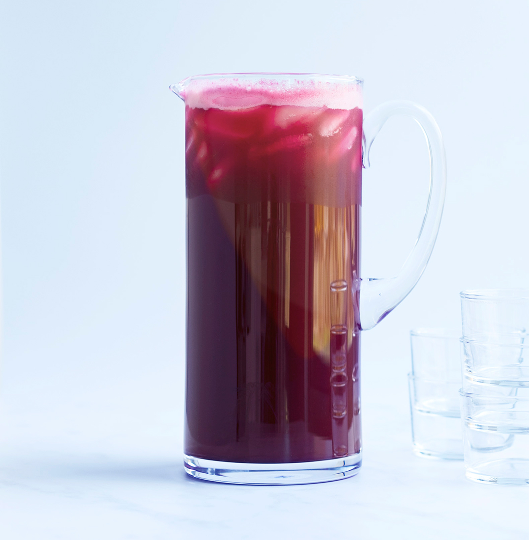 A tall glass pitcher of deep red happy heart juice 