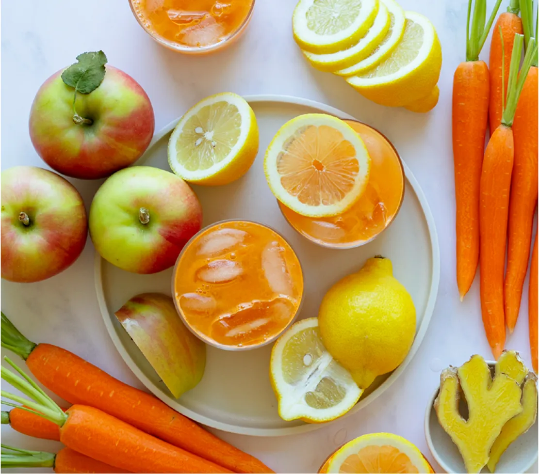 a plate with two glasses of warm glow juice surrounded by ingredients