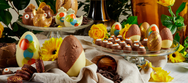 A colourful table setting of Easter chocolate eggs and chickens decorated with yellow flowers
