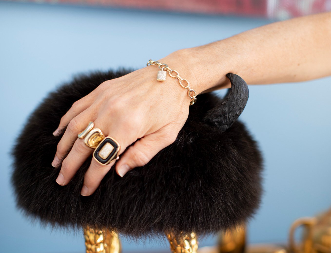 Gina Pell in front of bookcase wearing The Paloma Ring, Uncommon ring in Gold, The Double Apex Pendant, The Blade Pendant, The Fresh Cut Baguette Necklace, The Fresh Cut Oval Necklace, and The Fresh Cut Chandelier Drop Earrings