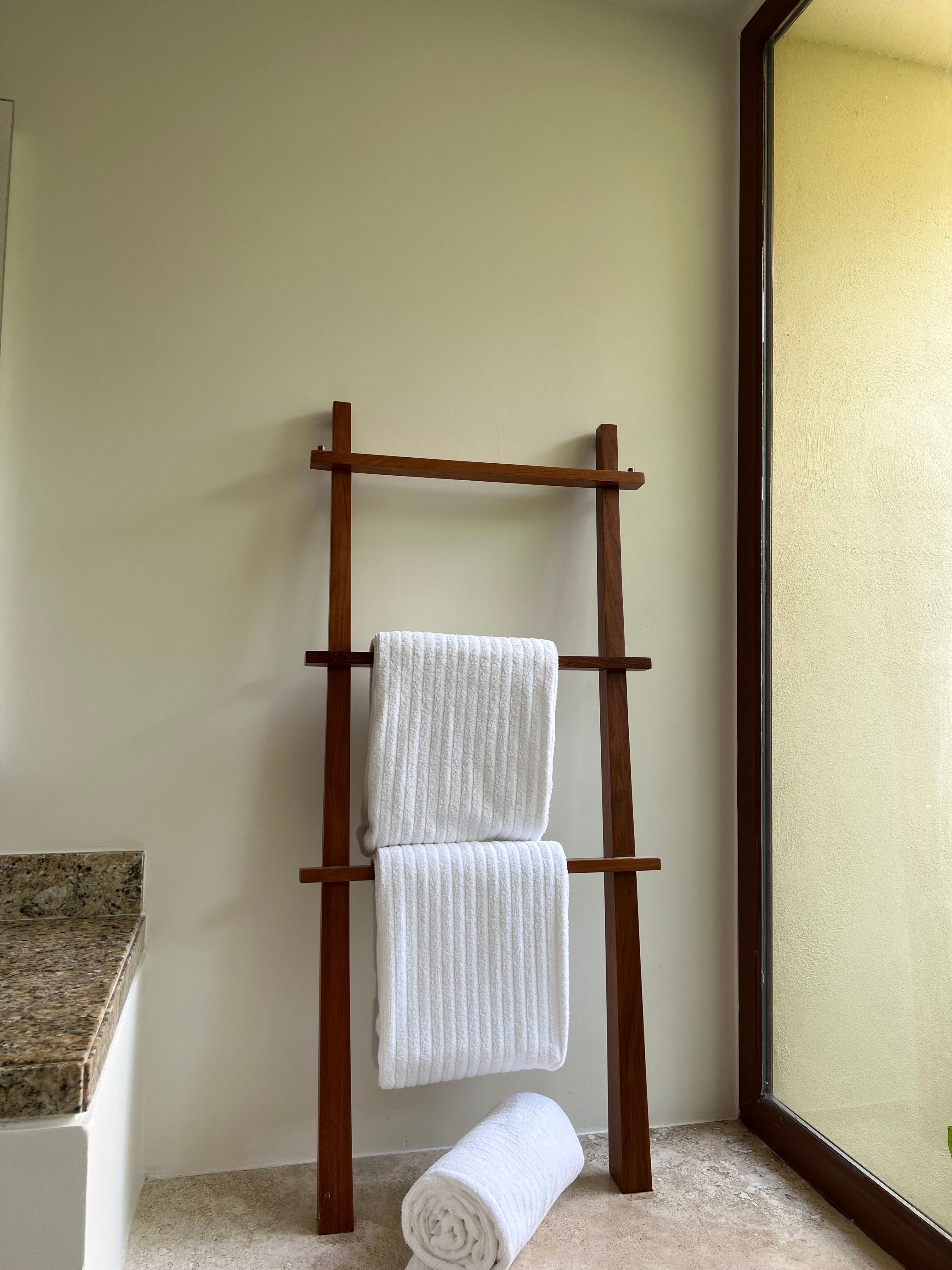 Rolled grey bath towels stacked on wooden shelves.