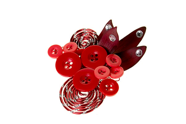 A unique and stylish boutonniere is created from coiled aluminum wire, large and small red buttons, leucadendron leaves, and some sticky rhinestones for a bit of bling.