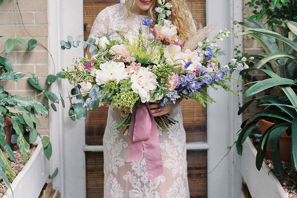 A luxurious Bespoke style wedding bouquet in pastel colors is finished rose colored satin ribbon.