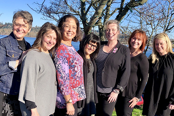 This lovely group photo of seven Floral Design Institute Instructors is taken outdoors under spring trees.