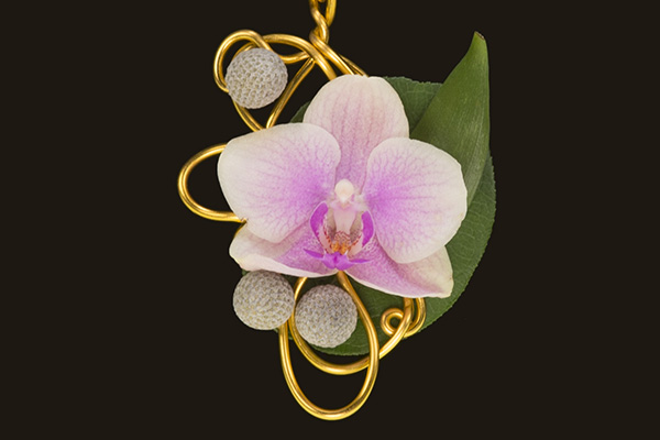 This beautiful floral pendant necklace designed by FDI Instructor, Michelle Headrick, features a miniature Phalaenopsis orchid and silver brunia on a gold base with Israeli ruscus as a backing.