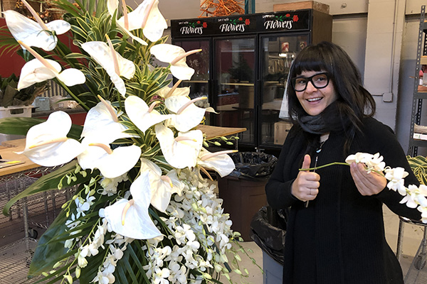 FDI Instructor Marisa Perring creates a large easel spray with white anthuriums and ivory orchids backed by a variety of foliage.