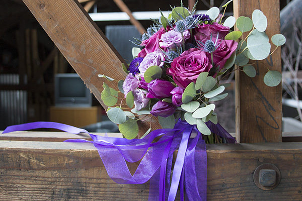 This gorgeous wedding bouquet, created by FDI Instructor Michelle "Chelle" Dummer, mixes cherry garden roses, pink spray roses, eryngium, red and purple tulips, silver dollar eucalyptus, and is finished with purple sheer and lavender satin ribbons. 