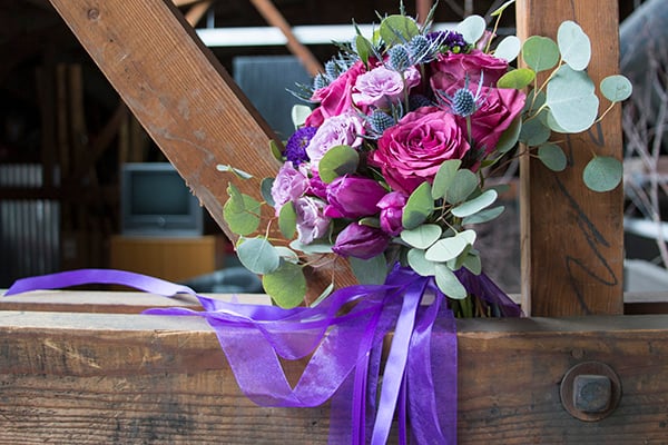 This gorgeous wedding bouquet, created by FDI Instructor Michelle "Chelle" Dummer, mixes cherry garden roses, pink spray roses, eryngium, red and purple tulips, silver dollar eucalyptus, and is finished with purple sheer and lavender satin ribbons. 