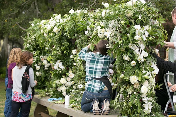 A large scale wedding floral installation is created using a crisp green and white color palette.