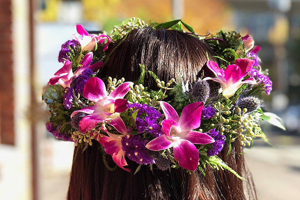 This lush floral crown in vibrant hues features hot pink orchids, purple violets, eryngium, and seeded eucalyptus.