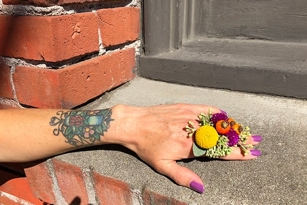 A stylish floral ring mixes orange rose hips, yellow craspedia, hot pink gomphrena, sedum, and seeded eucalyptus.