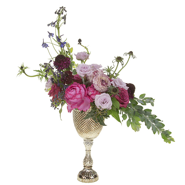 This beautiful tall wedding centerpiece mixes roses, peonies, ranunculus, eryngium, all in blush, pink and burgundy hues, in an elegant silver compote.