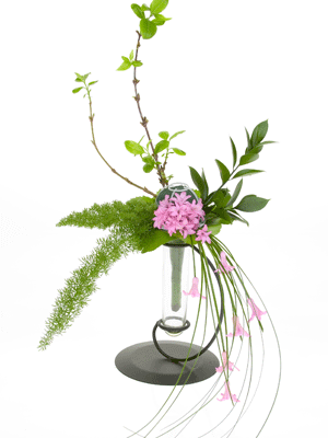 Add rhythmic, flowing lines extending in all directions using fox tail fern, Israeli ruscus, a forsythia branch, and bear grass.