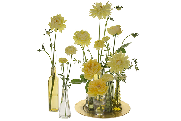 Lovely summer blooms in sunny yellow palette are placed in a variety of unique and colorful glass bottles, large and small, for a beautiful effect.