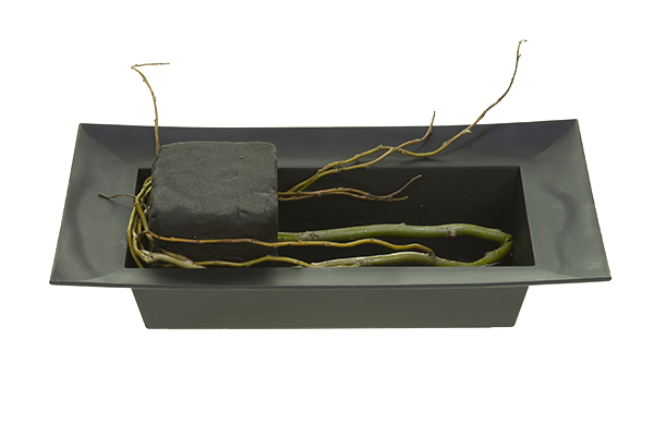 Place the floral foam asymmetrically on one side of the container and use the curly willow to wedge it into place.