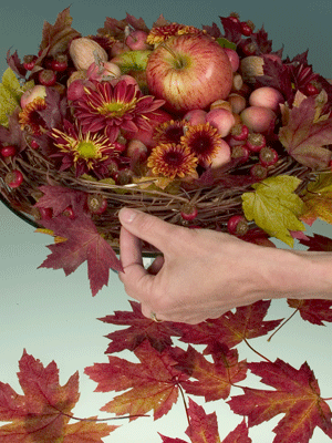 Set the grapevine wreath on the cake plate and tuck maple leaves into the weave of the wreath.