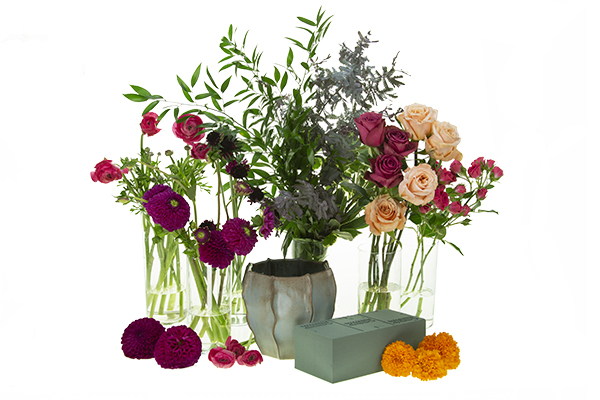 Materials for design include Italian ruscus, variegated pittosporum, acacia foliage, dahlias, marigolds, Blueberry roses, Shimmer roses, spray roses, ranunculus, scabiosa, floral foam, and a pottery vessel.