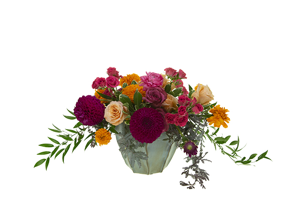 Insert the dahlias first, then add the marigolds, the standard roses, the spray roses and the ranunculus and layer the blooms to create depth in the design.