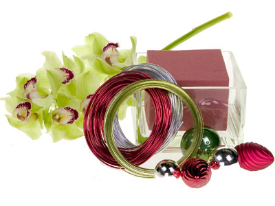 Materials for this holiday design include cymbidium orchid blooms, ornaments, floral foam, and colored flat wire.