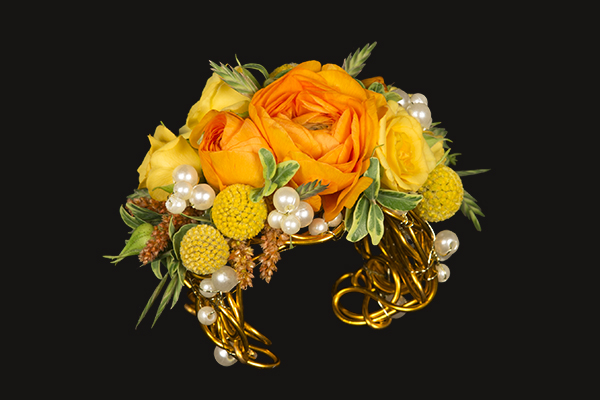 A gorgeous, over-the-top homecoming cuff with lots of bling is covered in orange roses, bright yellow spray roses, and sunshine colored craspedia for a beautiful style.