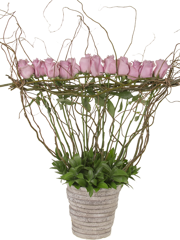 Pink roses are showcased in a dramatic contemporary Mother's Day floral design which uses curly willow as a natural armature and Israeli ruscus to cover the foam base mechanics.