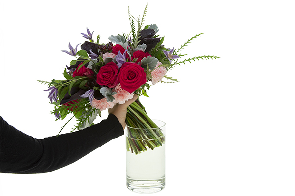 Placing the finished bouquet in a clear glass vase filled with water